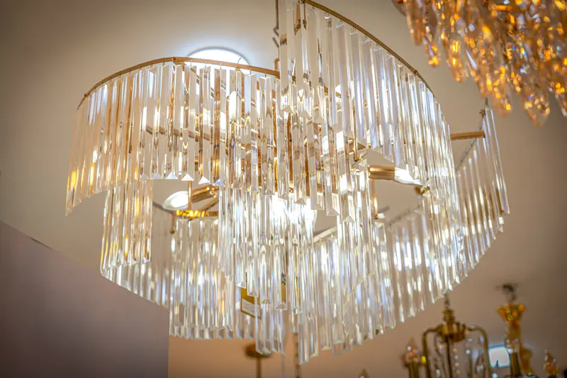 Lustre à pampilles de cristal sur structure dorée, exposé au showroom Alami Lights